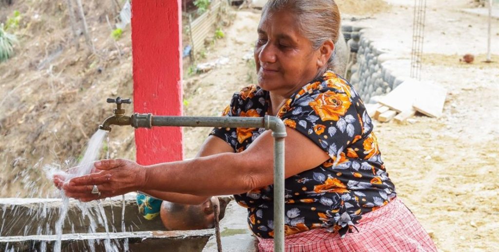 Mujer lavándose las manos en un grifo