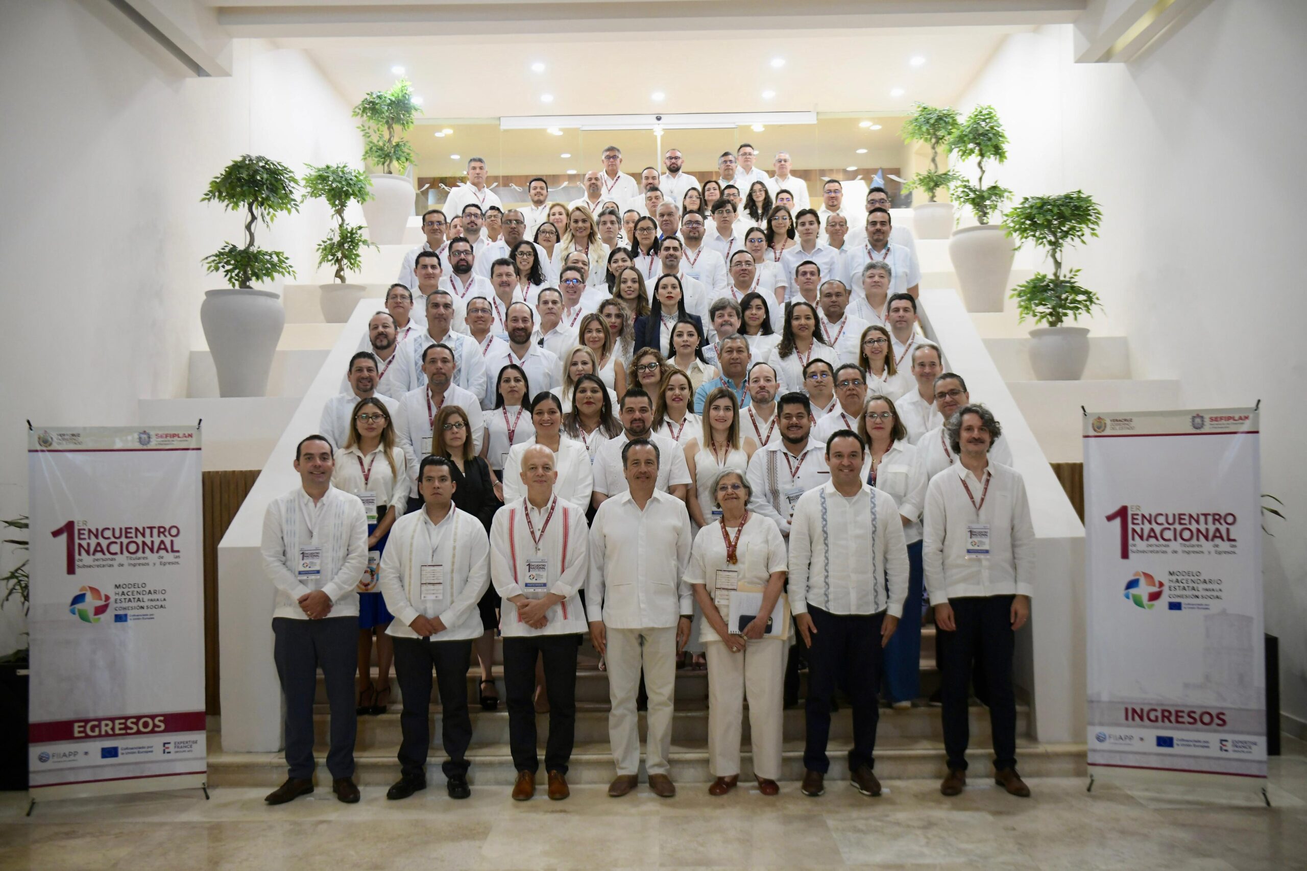 Un grupo de personas vestidas de blanco posando en unas escaleras en un evento llamado primer encuentro nacional